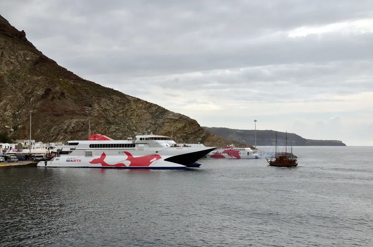 Athinios ferry port on Santorini with a fast ferry at the quay and a cliff behind