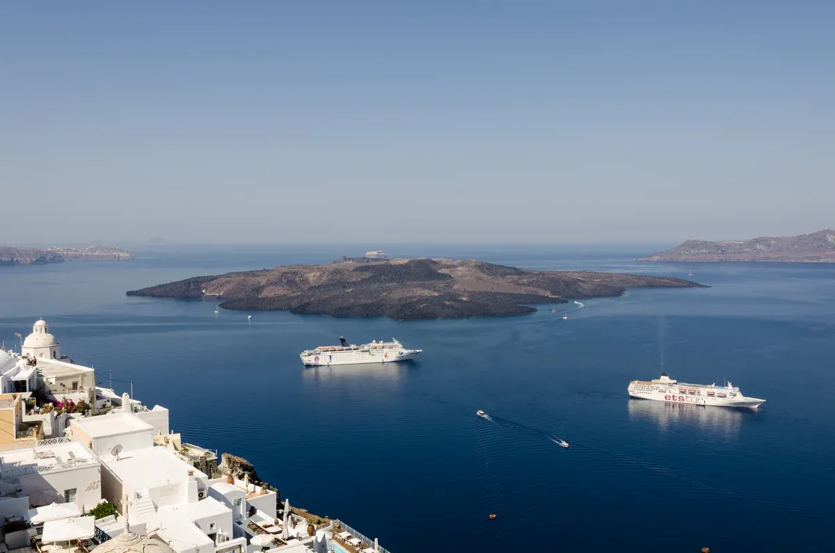 Nea Kameni volcanic island in the middle of the Santorini caldera with two ships anchored nearby