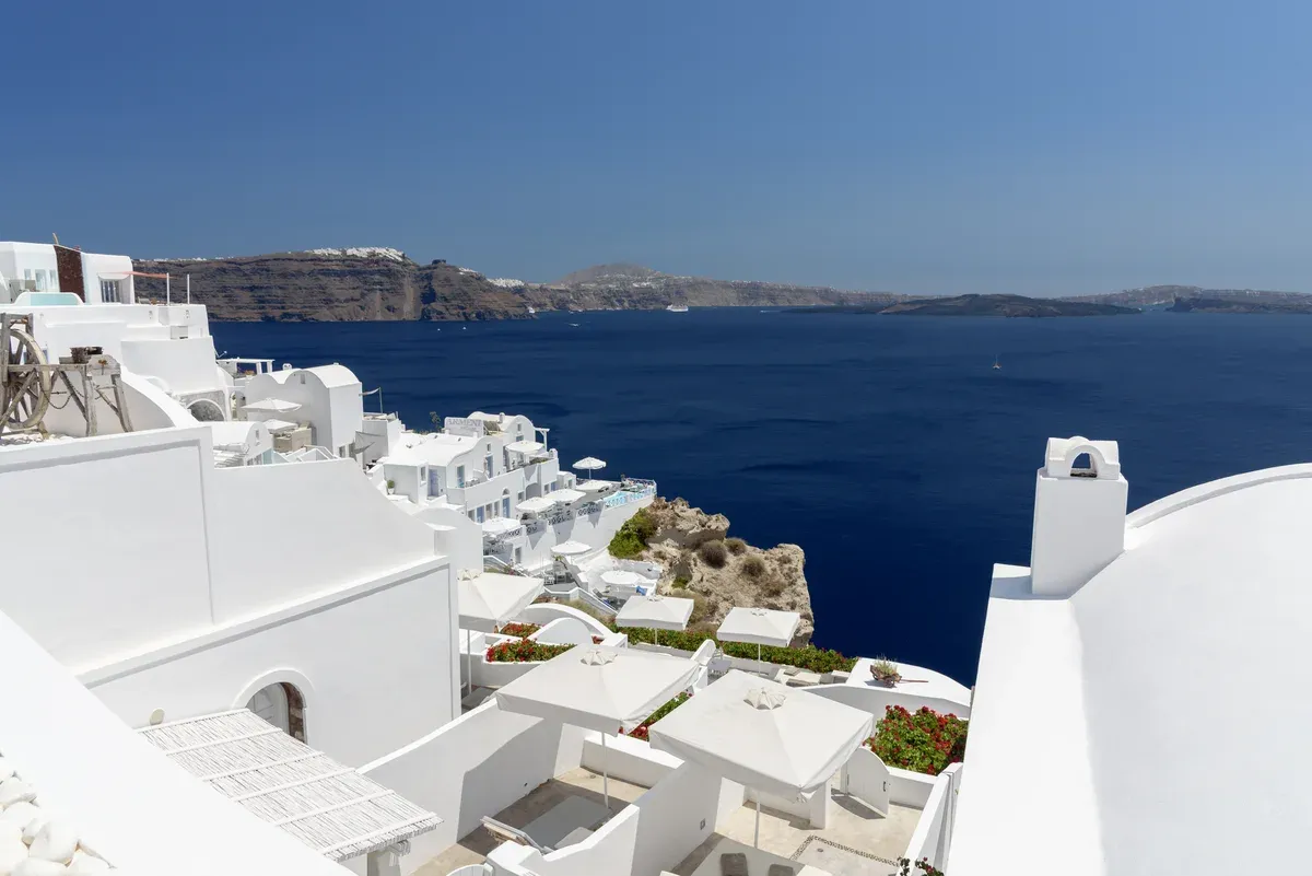 White domes and terraces of Oia above the deep blue caldera on a Santorini catamaran cruise from Oia